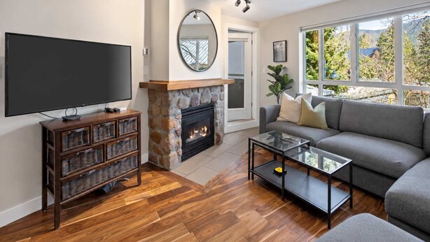 Una sala de estar con chimenea, televisor, sofá y un amplio ventanal.