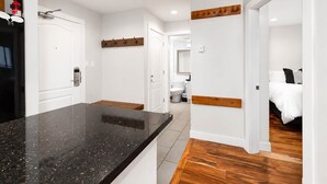 Una cocina moderna con encimera de granito, suelo de madera y paredes blancas.