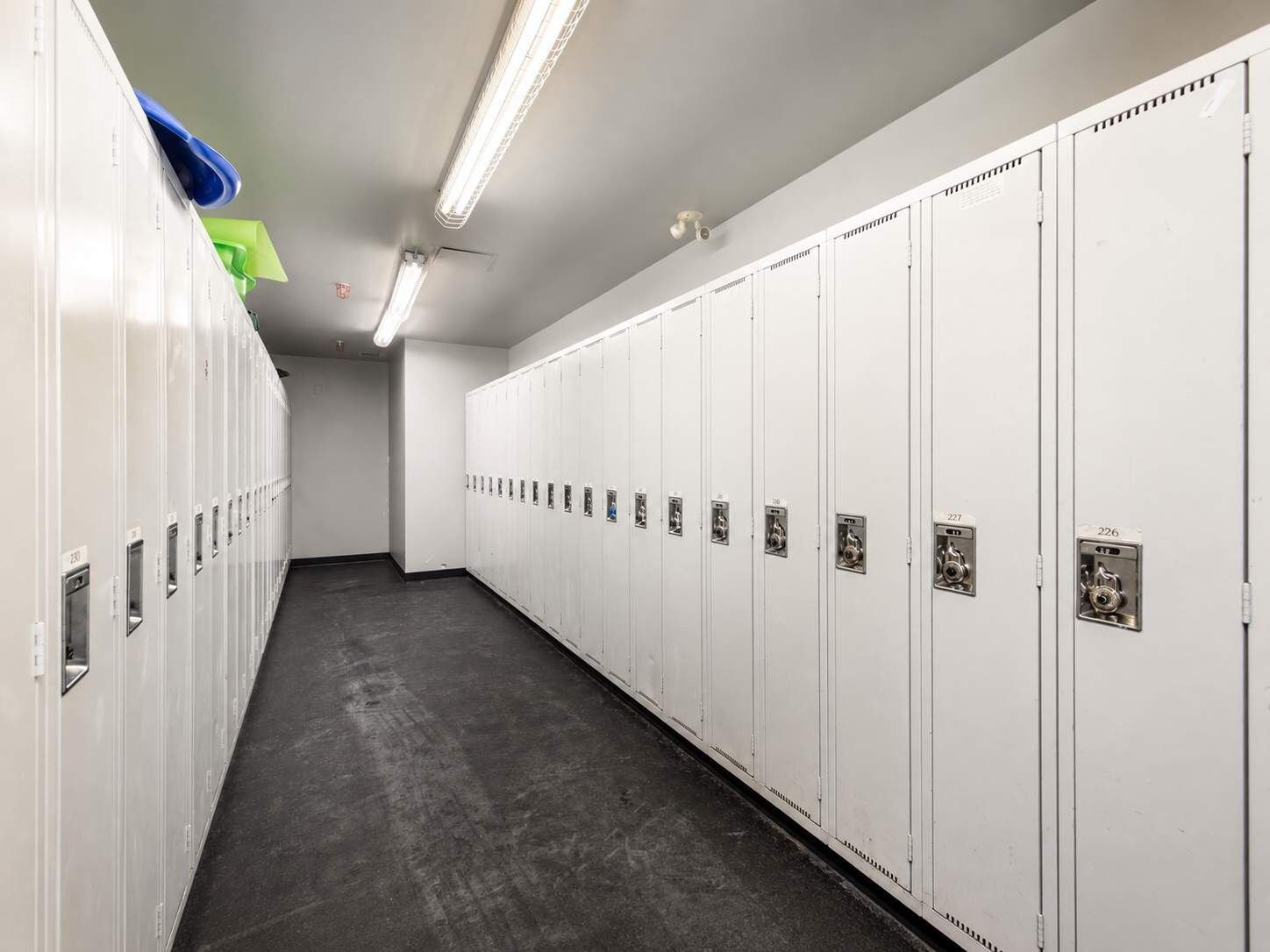 A clean, well-lit locker room with rows of lockers, some with numbers visible.