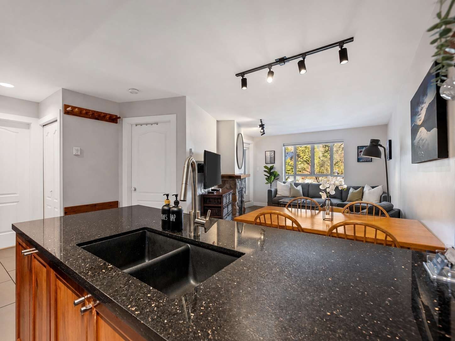 Una cocina moderna con un lavaplatos doble, armarios de madera y un comedor con mesa y sillas de madera.