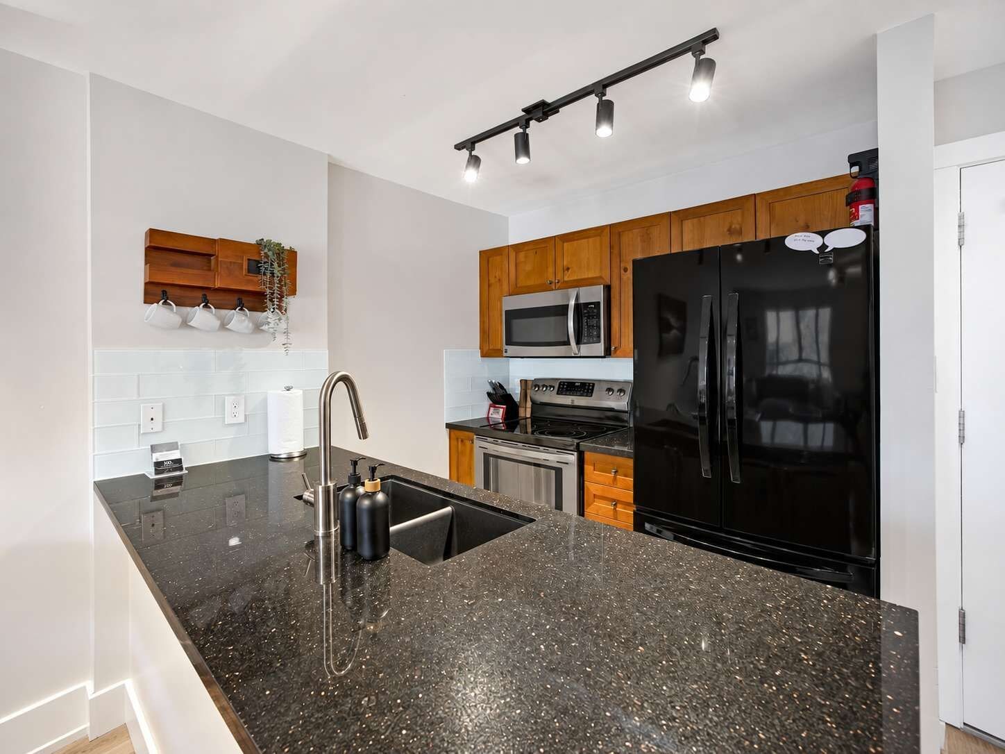A modern kitchen with granite countertops, stainless steel appliances, and wooden cabinets.