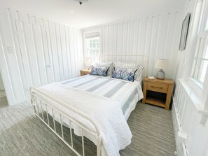 Un dormitorio con cama, mesitas de noche, ventana y radiador.