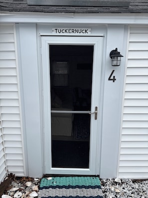 Una puerta blanca con un panel de vidrio, una placa con el nombre 'TUCKERNUCK' y el número '4' a la derecha.