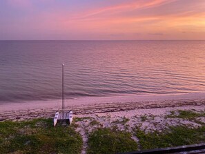 Ein Strand mit einer weißen Struktur, vermutlich einem Rettungsturm, und freiem Blick auf den Ozean.
