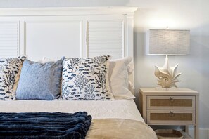 A bedroom with a bed, pillows, a bedside lamp, and a nightstand. - Gulf Front @ “The Coral” Breathtaking Sunsets! (Indian Shores)