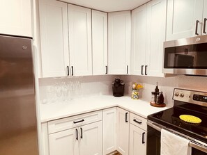 Una cocina con armarios blancos, un refrigerador de acero inoxidable, un microondas y un horno.