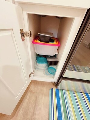 A storage cabinet with multiple compartments containing various containers and items. - Waterfront Bungalow Getaway | Sleeps 12 (Madeira Beach)