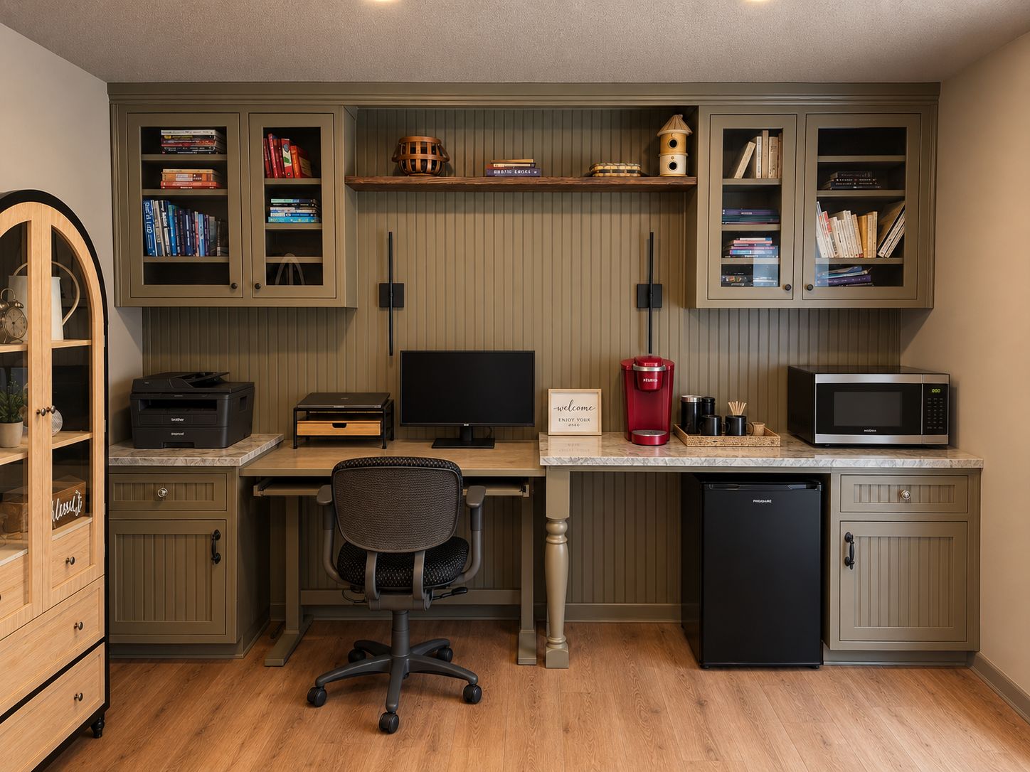 A home office with a desk, computer, chair, and built-in shelving with books and decorative items.