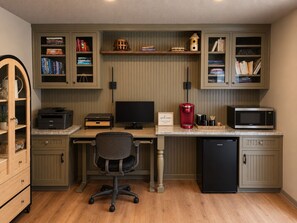 A home office with a desk, computer, chair, and built-in shelving with books and decorative items.