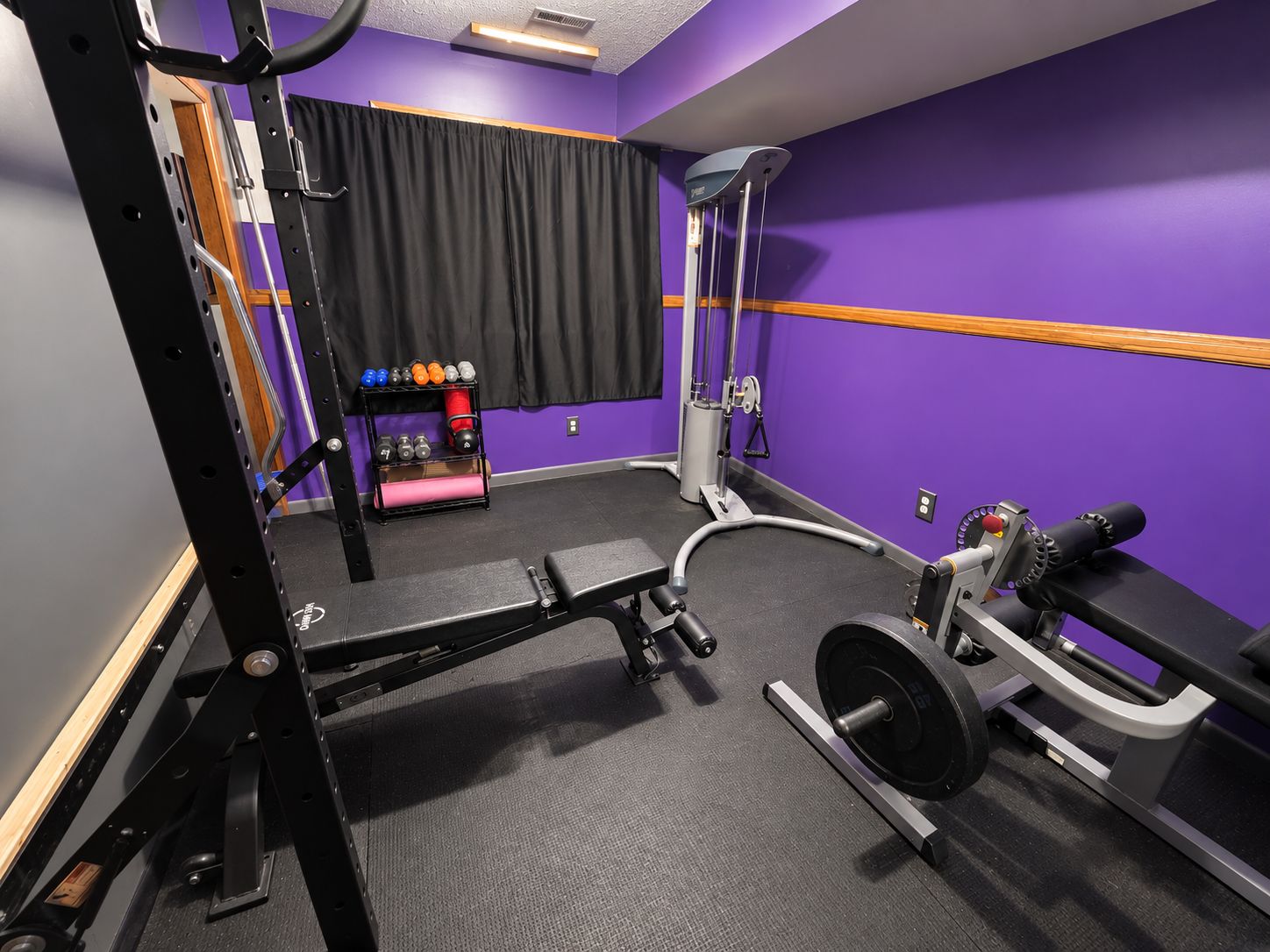 Ein Fitnessstudio mit Hantelgestell, Langhantelbank und verschiedenen Gewichten.