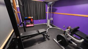 Ein Fitnessstudio mit Hantelgestell, Langhantelbank und verschiedenen Gewichten.