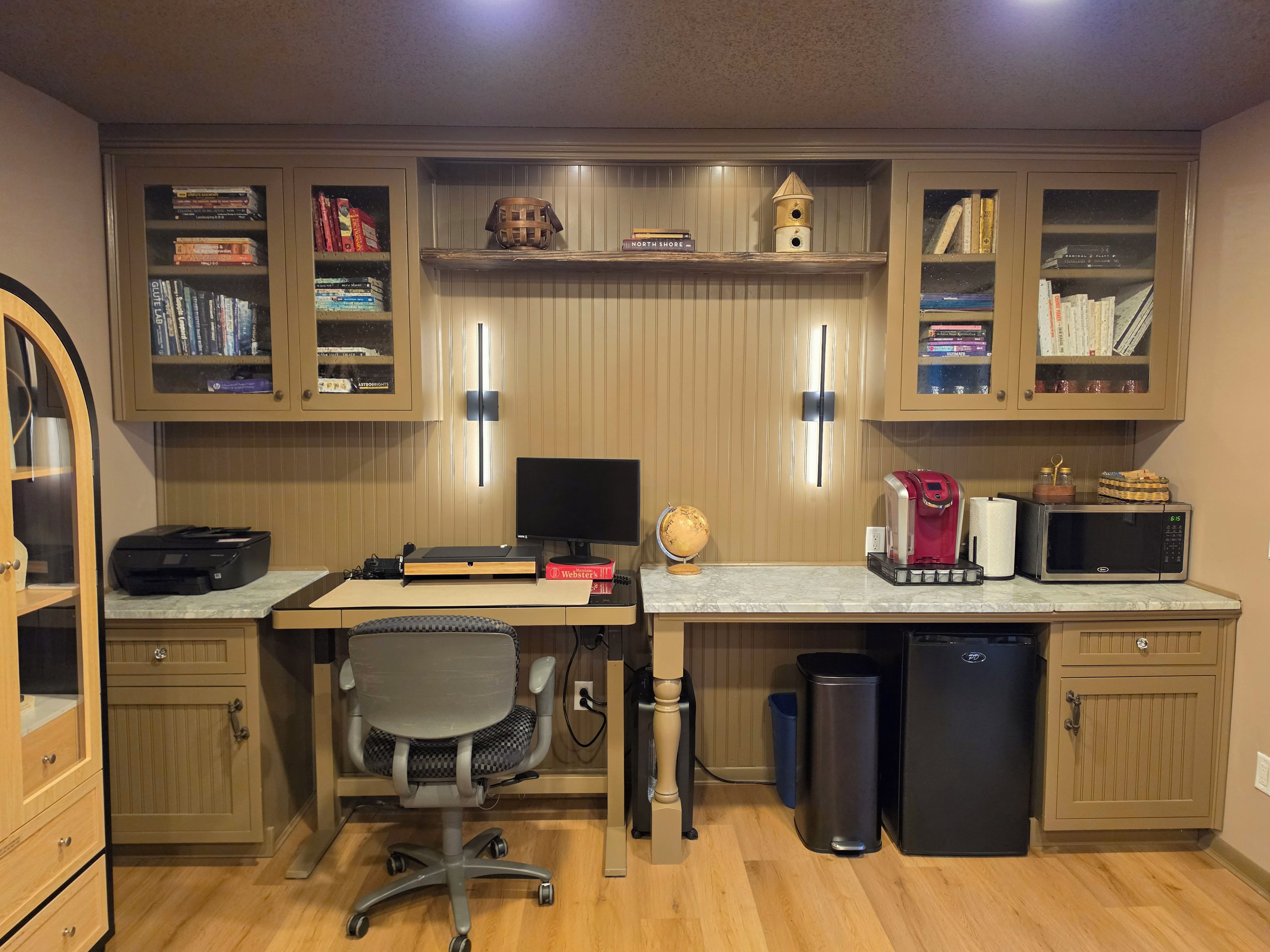 Un bureau à domicile équipé d’un bureau, d’un ordinateur, d’une bibliothèque et de divers accessoires de bureau.