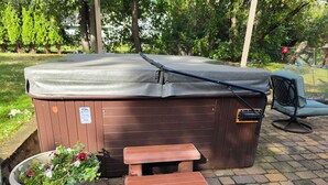 A hot tub with a wooden exterior, a bench, and a potted plant nearby. - Knot Northern Retreat & Spa: Hot Tub • Gym • Workspace (Minneapolis)