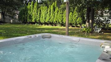 A hot tub with a wooden deck and a birdhouse in the background.