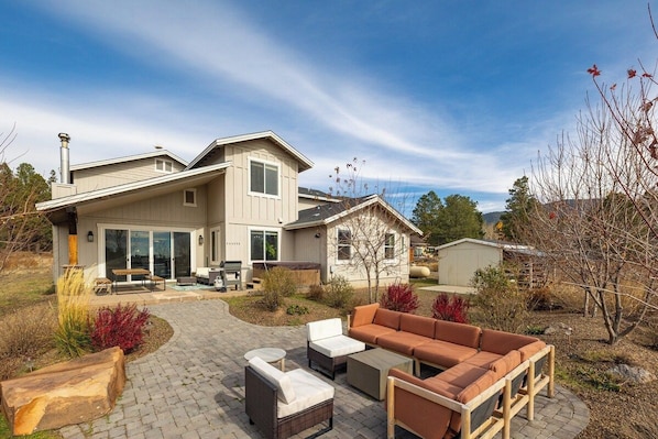 A modern two-story house with a patio area featuring outdoor furniture and a fire pit. - Wolfmoor spacious cabin with trail access (Flagstaff)