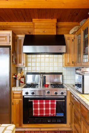 A kitchen with wooden cabinets, a stainless steel stove, and a tiled backsplash.