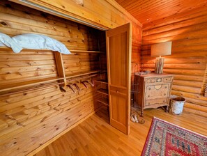 A wooden interior with a bed, a dresser, and a hanging shoe rack.