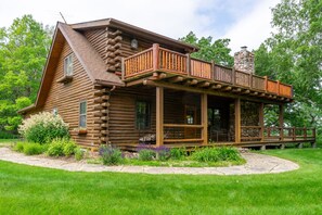 A log cabin with a porch and a stone chimney.