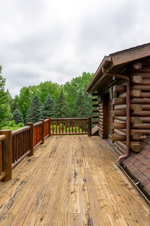 A wooden deck with a railing, surrounded by trees. - Skyline Log Cabin • River Views + Screened Patio (Wabasha)