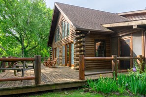 A log cabin with a wooden deck and a wooden fence.