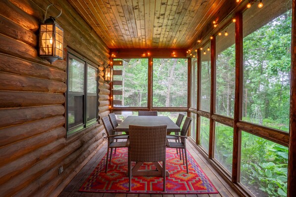 L’intérieur d’une cabane en rondins comprend un coin repas, de grandes fenêtres et une vue sur la forêt.
