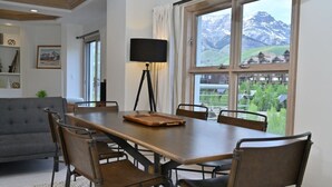 A dining area with a table, chairs, a lamp, and a view of mountains through a window. - 2 Bedroom Peaks Penthouse with stunning views, ski-in/ski-out, pools/spa/golf (Telluride)