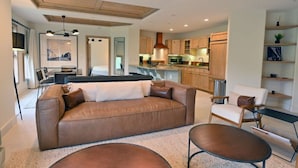 A modern living room with a brown leather sofa, a coffee table, and a dining area with a table and chairs. - 2 Bedroom Peaks Penthouse with stunning views, ski-in/ski-out, pools/spa/golf (Telluride)
