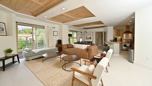 A spacious living area with a large sofa, a coffee table, and a dining table. There is a kitchen in the background with modern appliances. - 2 Bedroom Peaks Penthouse with stunning views, ski-in/ski-out, pools/spa/golf (Telluride)