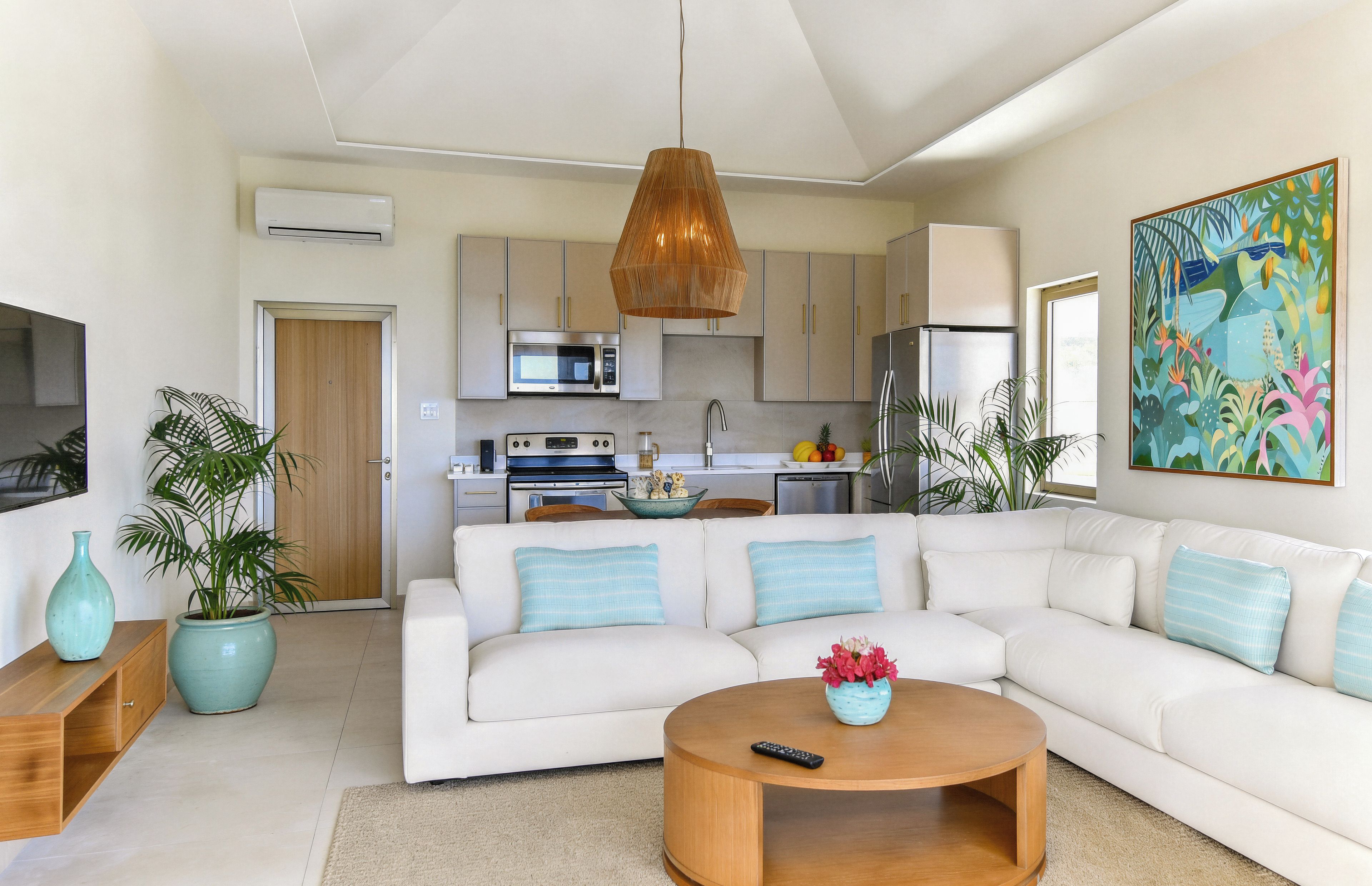 A modern living room with a white sofa, a wooden coffee table, and a kitchen in the background.