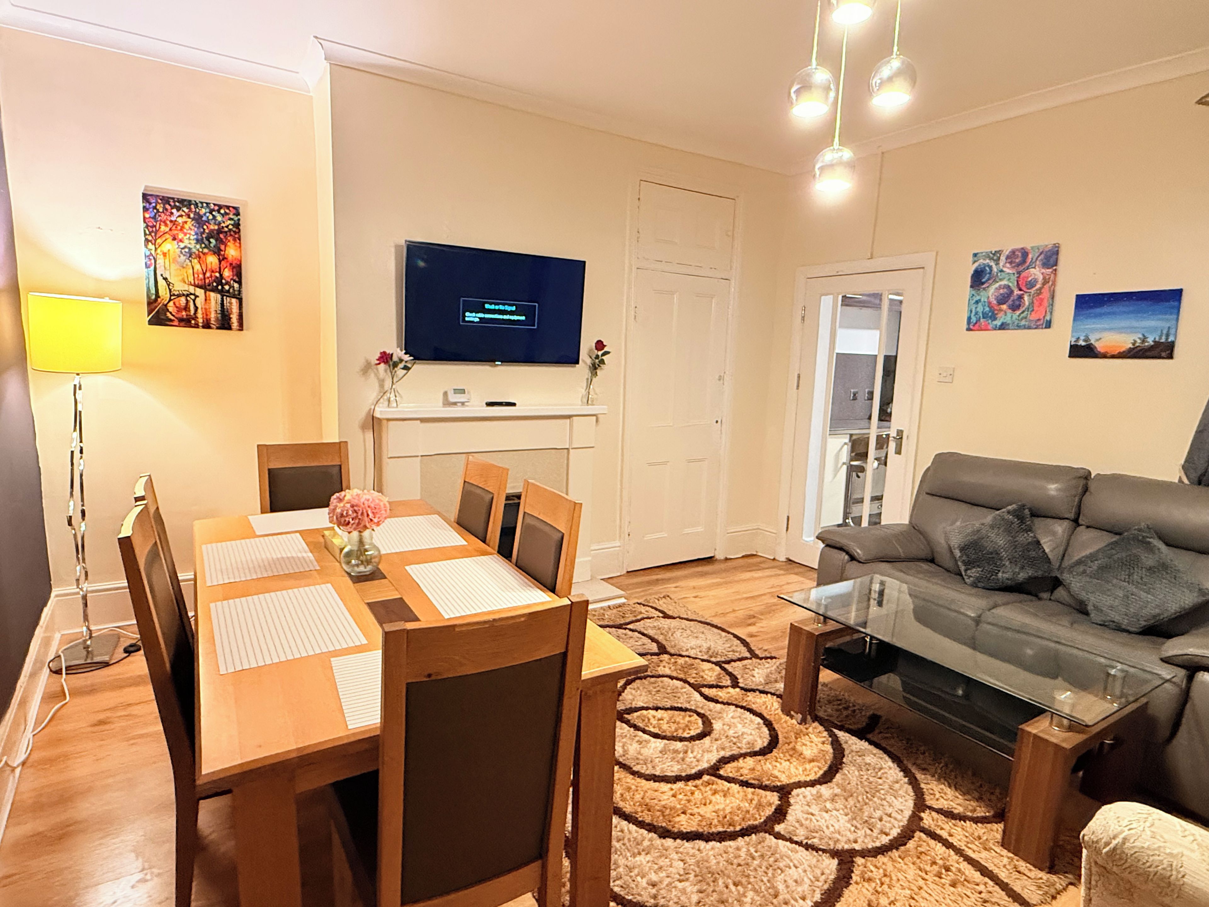 A modern living room with a dining table, sofa, and TV.