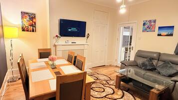 A modern living room with a dining table, sofa, and TV.