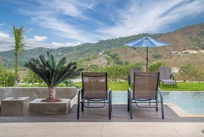 A deck with two chairs and an umbrella overlooking a pool and a mountainous landscape. - Hilltop Paradise with Pool: 3BR in Playa del Coco (Coco)