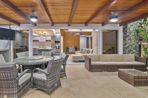 An outdoor patio area with wicker furniture, a glass-top table, and a built-in kitchen area. - Hilltop Paradise with Pool: 3BR in Playa del Coco (Coco)
