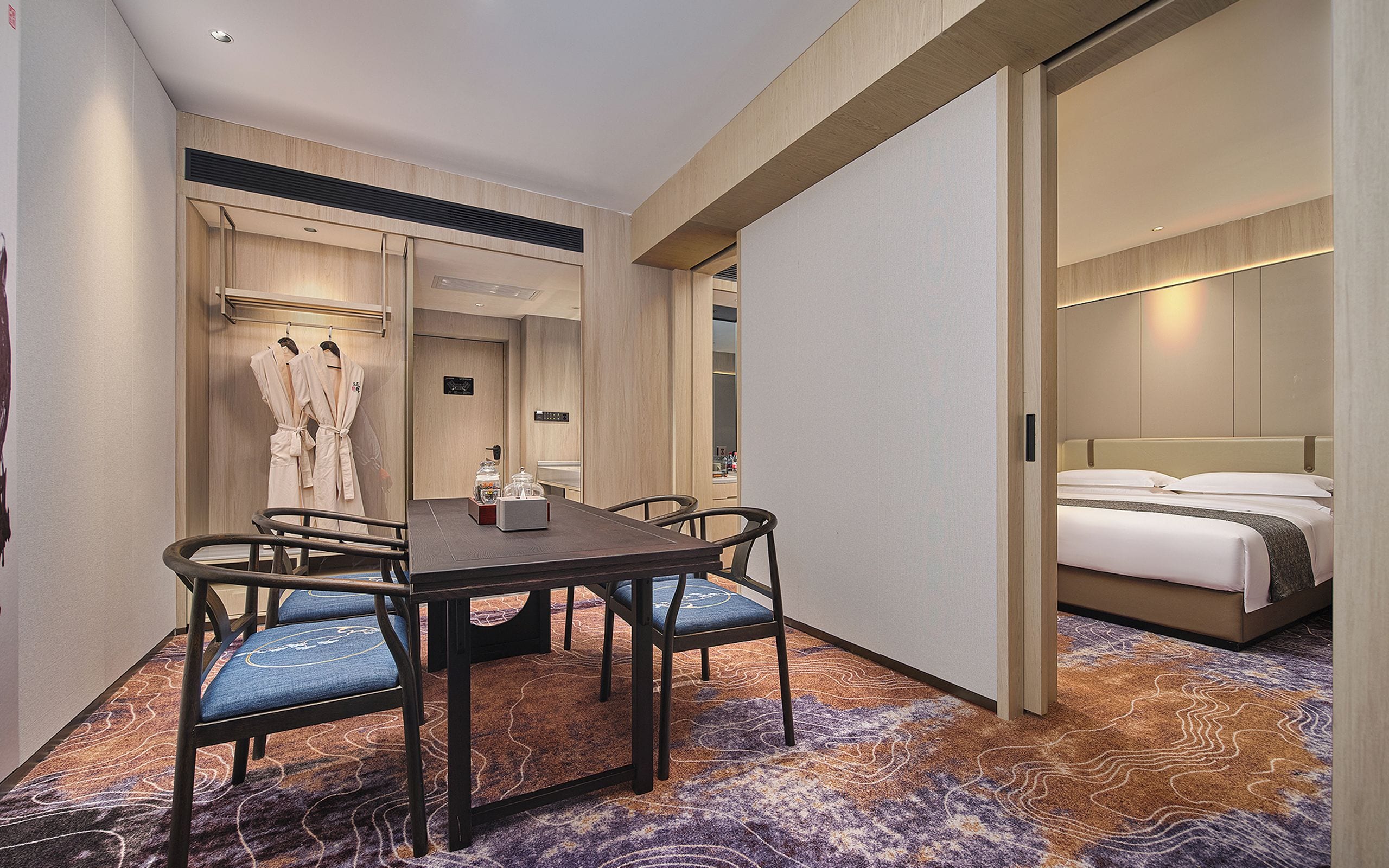 A hotel room with a dining area, a bed, and a bathroom.