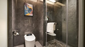 Een moderne badkamer met toilet, een douchecabine van glas en een handdoekhouder aan de muur.