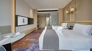 Quarto de hotel com cama, mesa de cabeceira, abajur e vista para a cidade pela janela.