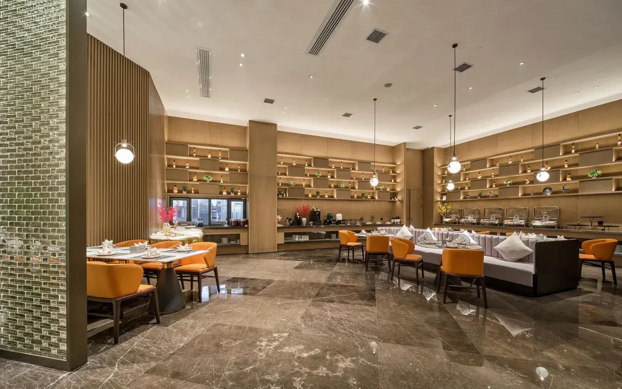 A modern restaurant interior with marble flooring, orange seating, and wooden shelving with decorative items.