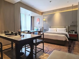 Habitación de hotel con cama, mesita de noche y zona de comedor con sillas y mesa.