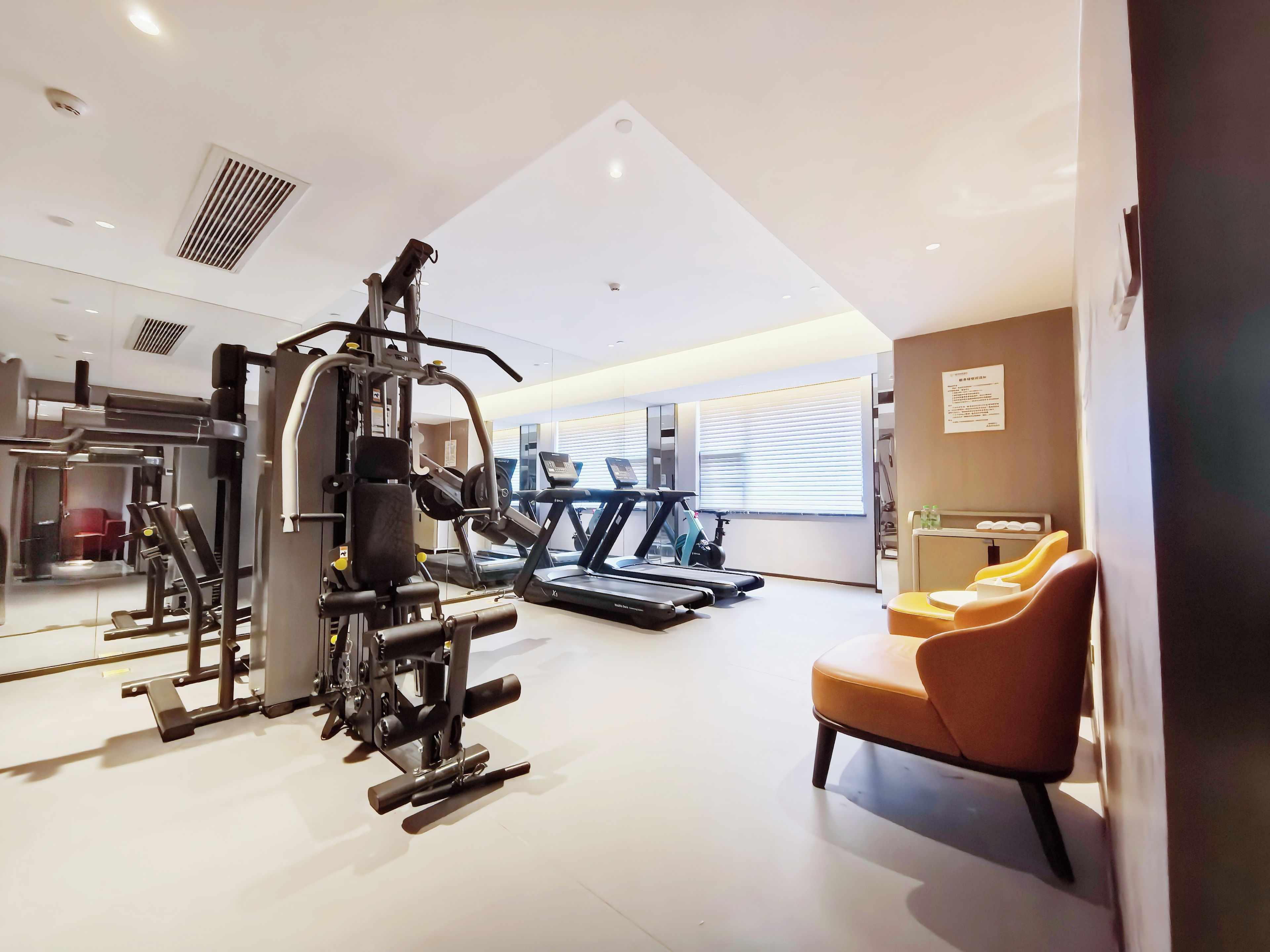 Un gimnasio con equipamiento de ejercicio, cinta de correr y sillón de masajes.