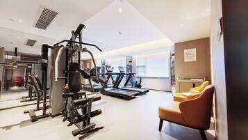 Un gimnasio con equipamiento de ejercicio, cinta de correr y sillón de masajes.