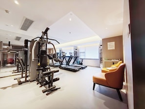 A gym with exercise equipment, a treadmill, and a massage chair.