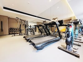 Un gimnasio moderno con cintas de correr, máquinas de pesas y un espejo grande.