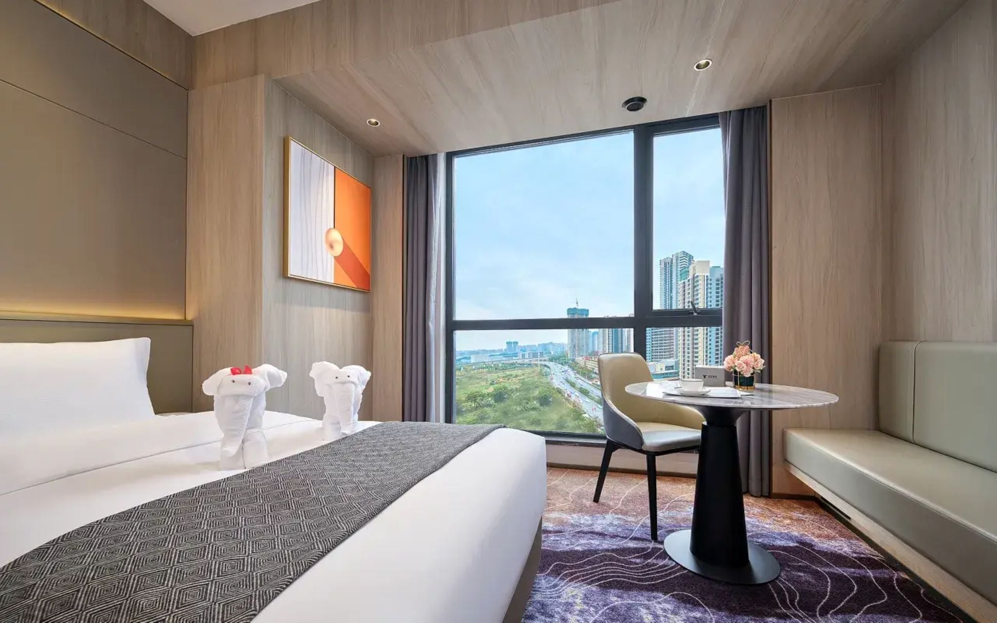 Une chambre d’hôtel dotée d’un grand lit, d’un canapé, d’une table à manger et offrant une vue sur le paysage urbain.