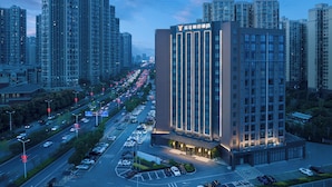 Een hoog hotel met modern design, omringd door een levendige stadsstraat en andere hoogbouw.