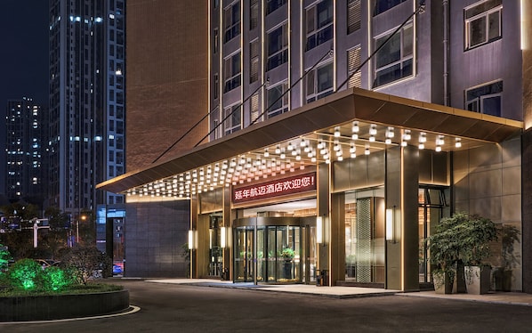 A hotel entrance with a modern design, featuring a glass facade and a welcoming sign.