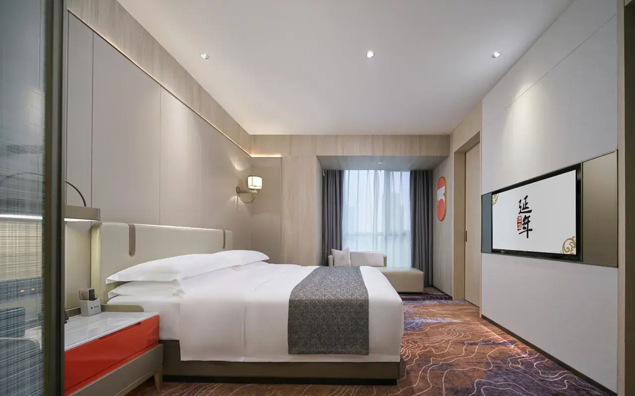 A hotel room with a bed, bedside table, and a large window.