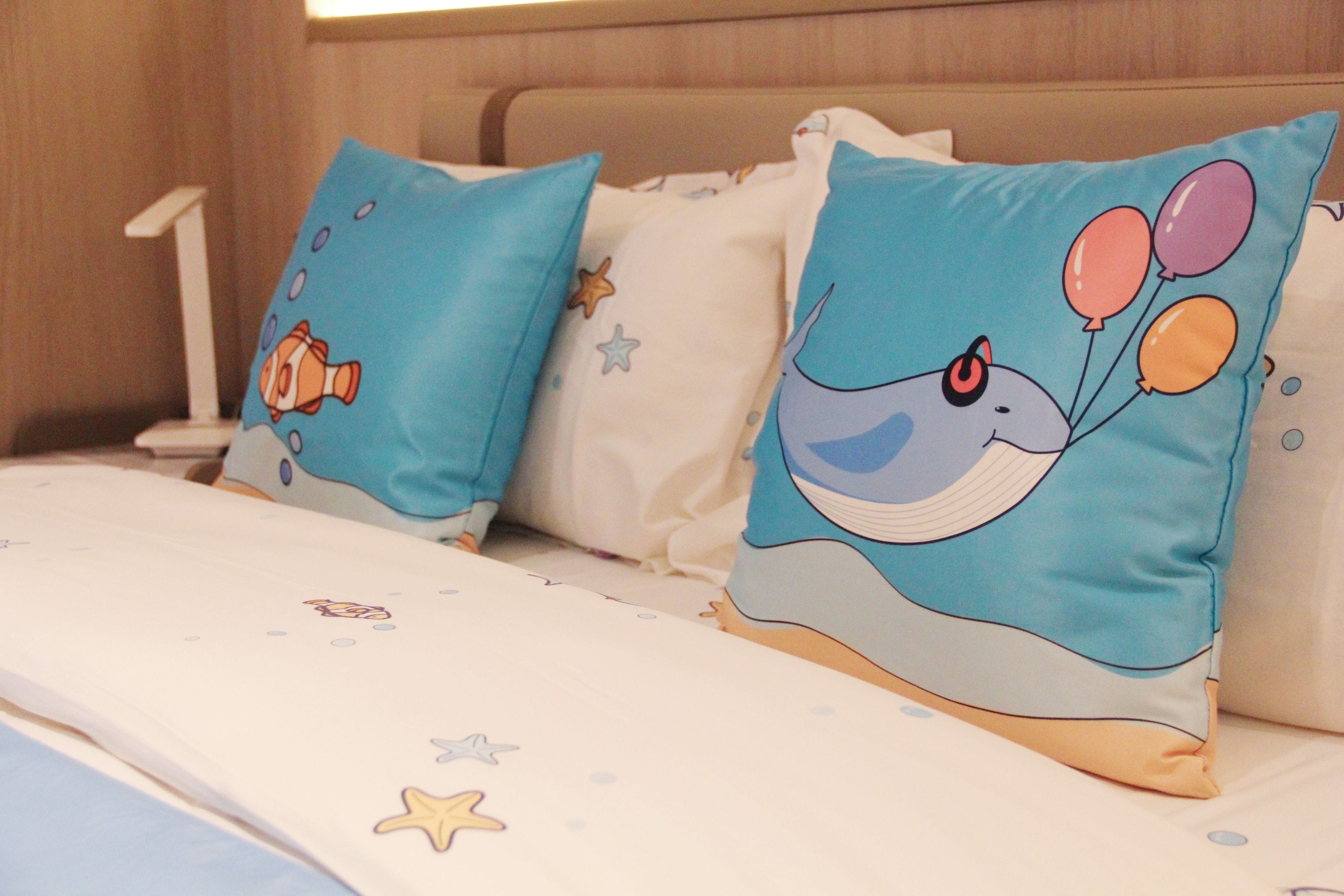 A bed with two pillows featuring cartoon characters and stars.