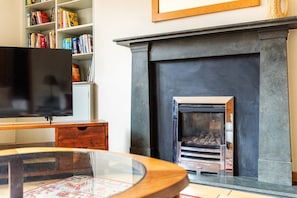 A living room with a fireplace, a television, a bookshelf, and a coffee table. - Stylish Notting Hill Two Bed near Bayswater (London)