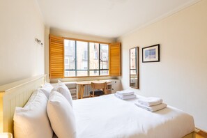 Ein Hotelzimmer mit Bett, Schreibtisch und einem Fenster mit Jalousien.