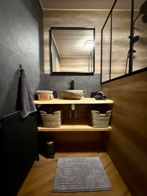 A bathroom with a wooden vanity, a black sink, a mirror, and a towel hanging on the wall. - Chamrousse CAP 2000 Apartment (Chamrousse)